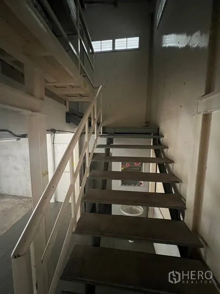 Shophouse for rent in Watthana, Bangkok - Narrow metal staircase ascending to a mezzanine level.