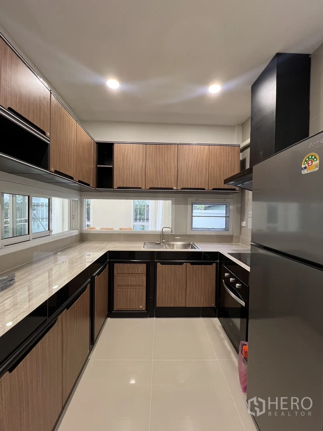 Detached House for rent in Saphan Sung, Bangkok - U-shaped kitchen with wood cabinets, marble-look counters and sink.