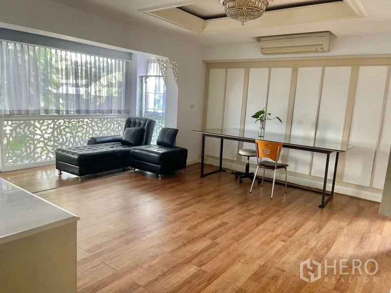 Home Office for rent or sale in Suan Luang, Bangkok - Bright open‑plan room with corner leather sofa and long work desk beside wide windows.