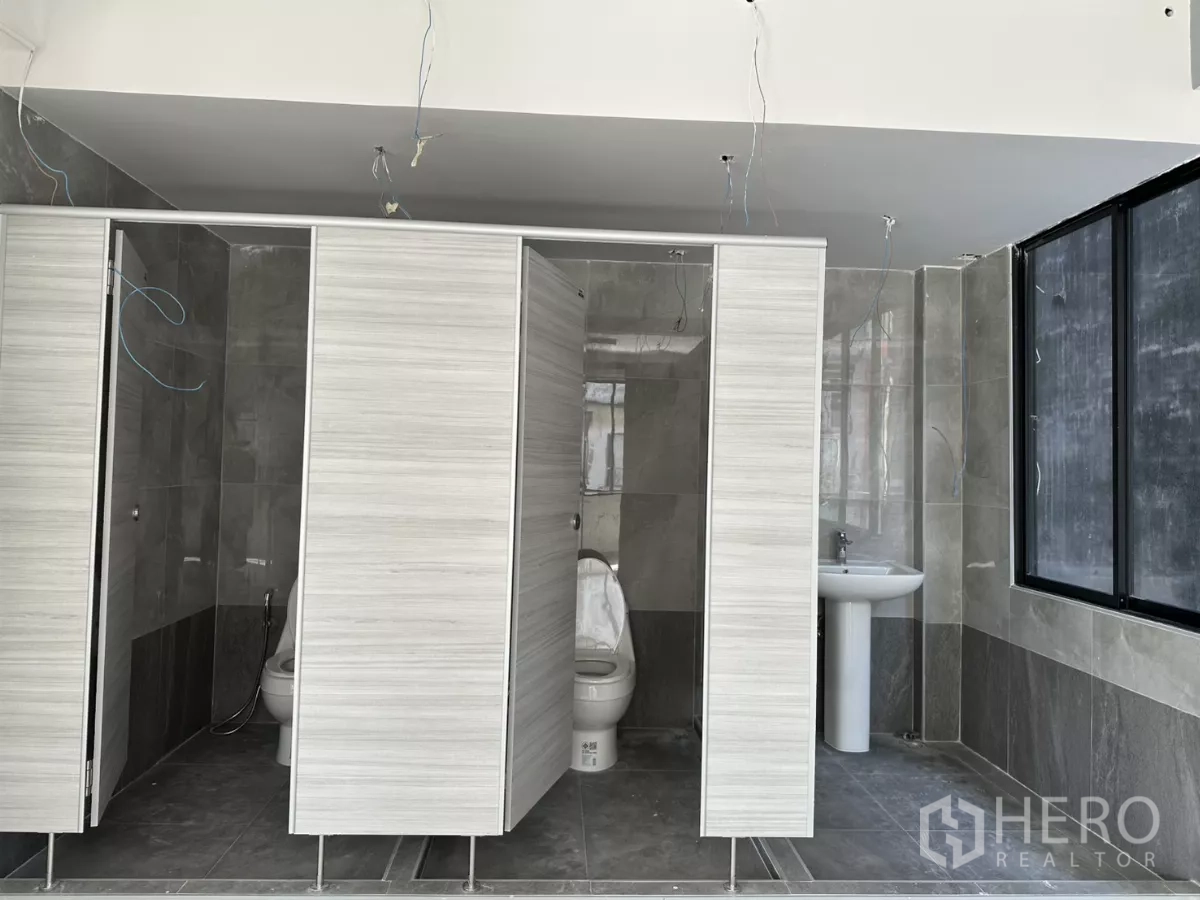 办公空间 出租在Phra Khanong, Bangkok - 瓷砖墙面的卫生间，配多间隔断与台盆，等待最终安装。