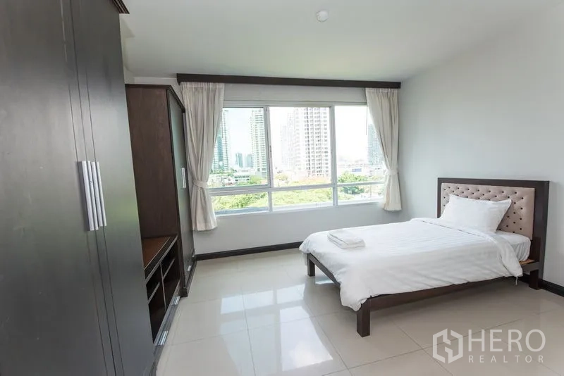Condominium for rent in Sathon, Bangkok - Sunlit bedroom with picture window, tiled floor and city outlook.