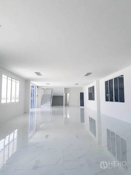 Warehouse for rent in Samut Prakan - Open office hall with wide windows, sliding glass entry, and glossy floors.