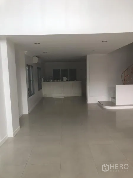 Home Office for rent or sale in Watthana, Bangkok - Open-plan ground floor with tiled flooring, white pantry cabinetry, and a curved staircase.