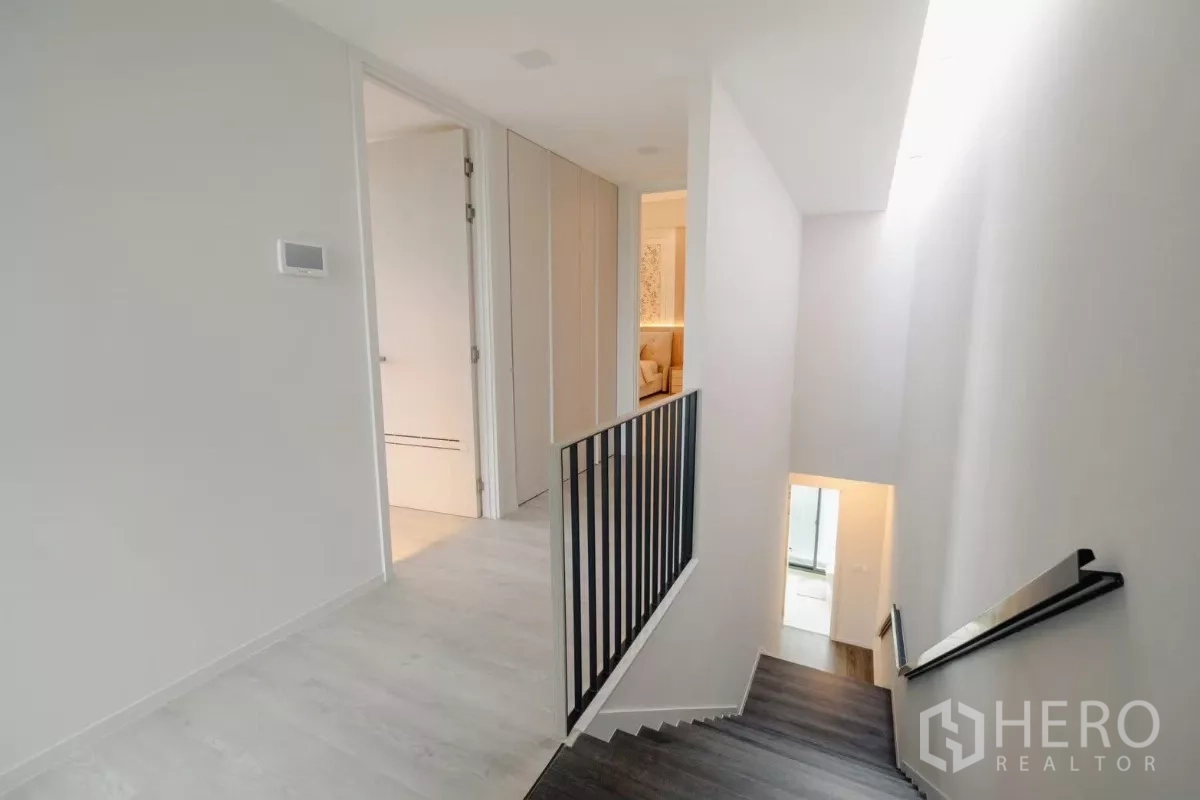 Detached House for rent in Saphan Sung, Bangkok - Bright stair hall with white walls, black metal railing, and wood steps leading to the bedroom level.
