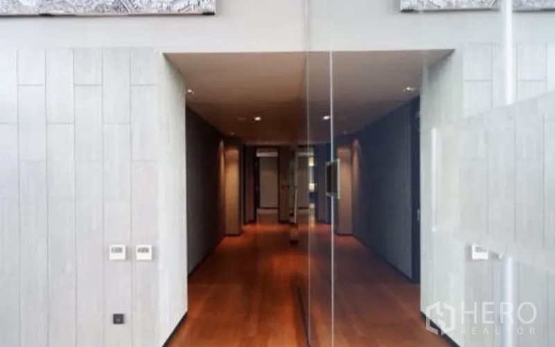 公寓 出租在Sathon, Bangkok - 走廊铺木地板，筒灯照明，玻璃墙通向主要空间。
