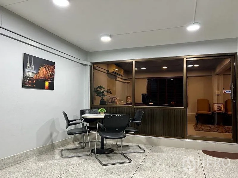Shophouse for sale in Bang Kho Laem, Bangkok - Indoor terrace with round table and chairs beside a glass-walled office.
