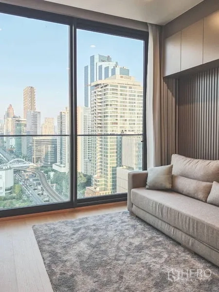 Condominium for rent in Bang Rak, Bangkok - Sofa by large sliding glass doors with expansive high-rise city views.