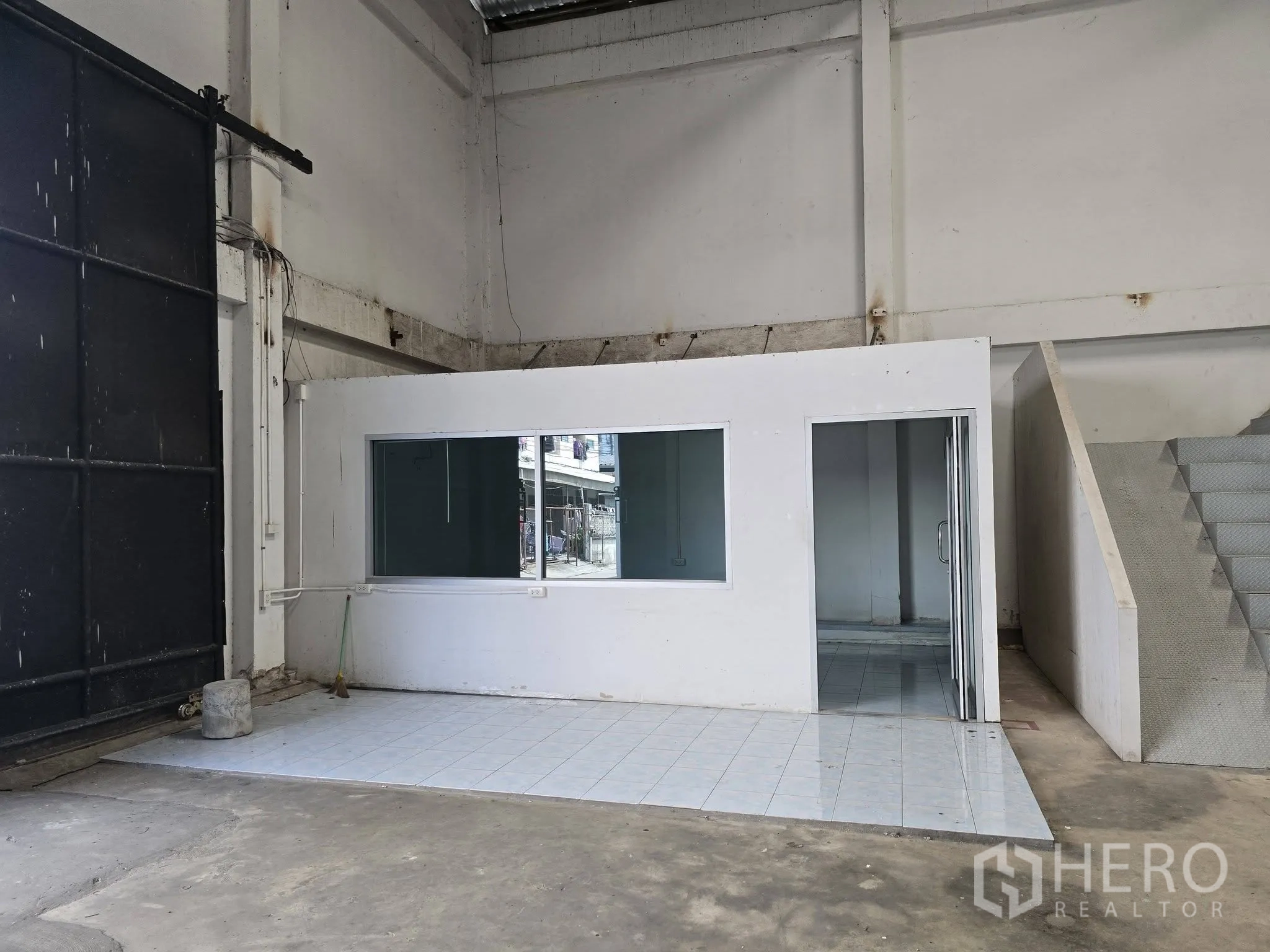 Warehouse for rent in Bang Na, Bangkok - Built-in office room inside the warehouse with large windows and a sliding door near the main entry gate.