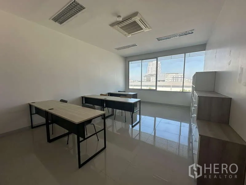 Office Space for rent in Prawet, Bangkok - Furnished workspace with desks and chairs facing a large window and city outlook.