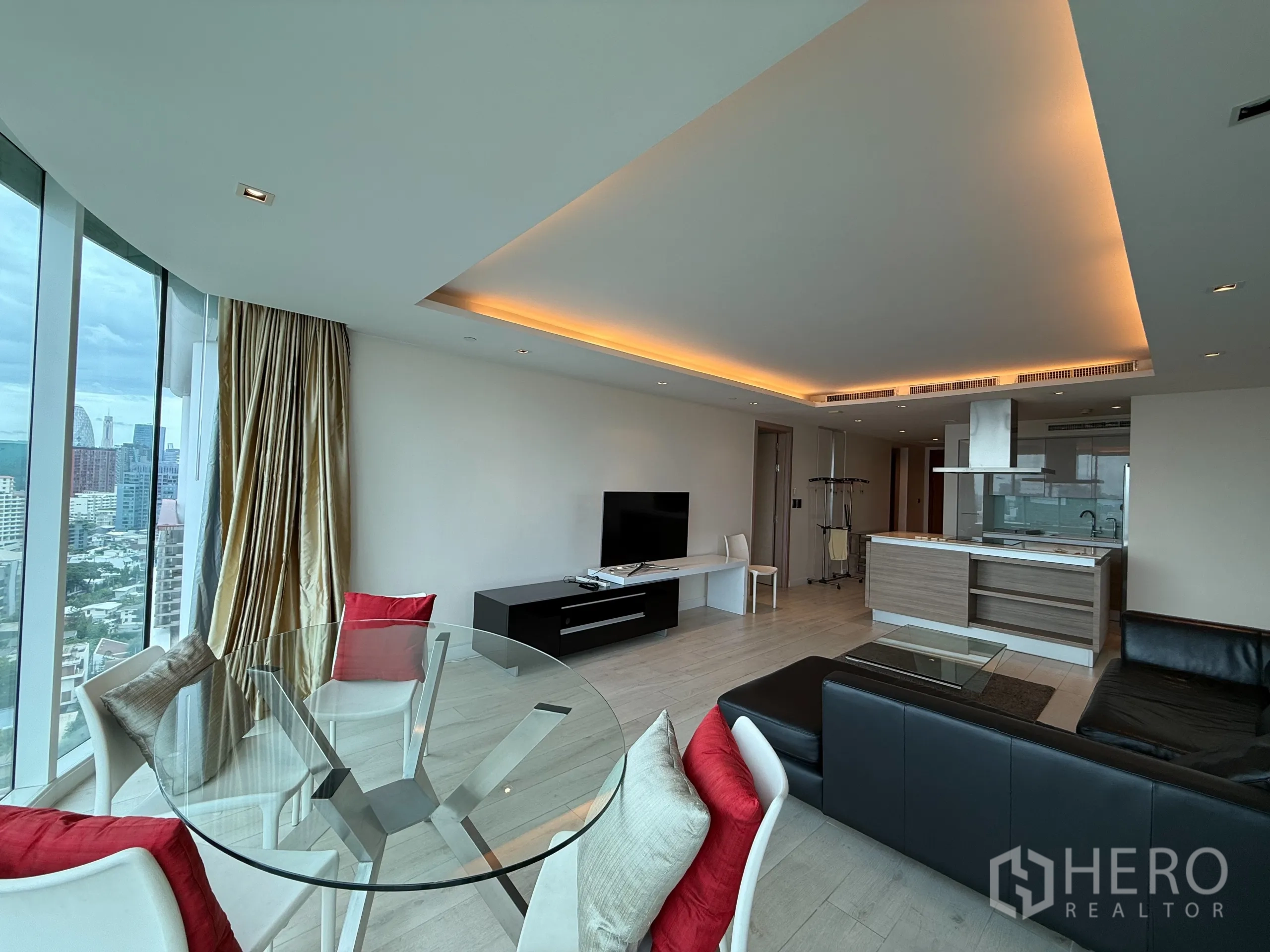 คอนโด ให้เช่าในPhaya Thai, Bangkok - ห้องนั่งเล่นและรับประทานอาหารแบบโอเพนแปลน โต๊ะกระจก โซฟาหนัง ชุดทีวี เคาน์เตอร์ครัว และผนังกระจกสูงจรดเพดานมองเห็นสกายไลน์กรุงเทพฯ