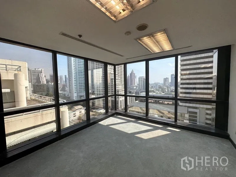 Office Space for rent in Khlong Toei, Bangkok - Corner office with floor-to-ceiling windows and Bangkok skyline views filling the room with daylight.