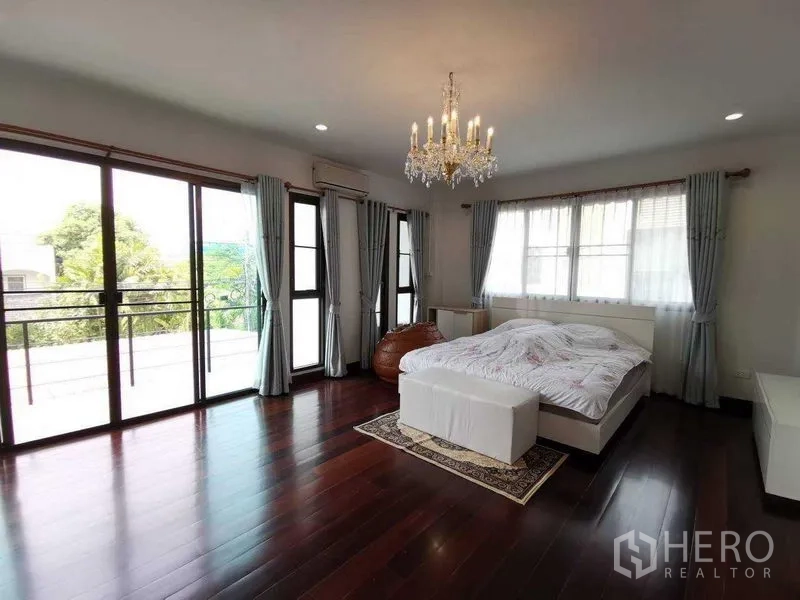 Detached House for rent in Prawet, Bangkok - Large master suite with wide balcony access, glass doors, chandelier and dark wood floors.