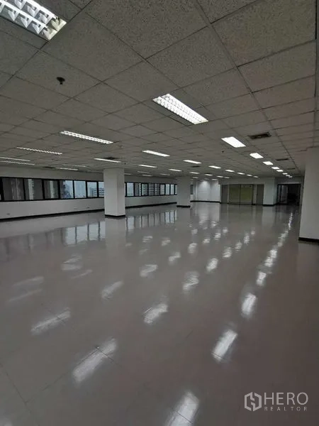 办公空间 出租在Watthana, Bangkok - 宽敞办公楼层，立柱、顶灯与面向城市的窗户。