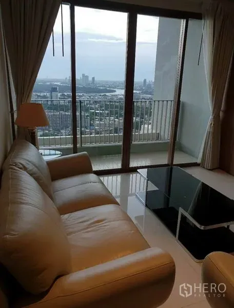 คอนโด ให้เช่าในKhlong Toei, Bangkok - โซฟาและโต๊ะกลางกระจกติดระเบียง กระจกบานเลื่อนชมวิวเมืองกว้าง