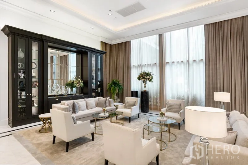 Condominium for rent in Pathum Wan, Bangkok - Grand residents’ lounge with sofas, armchairs, glass tables, floor-to-ceiling drapes, and a mirrored cabinet.