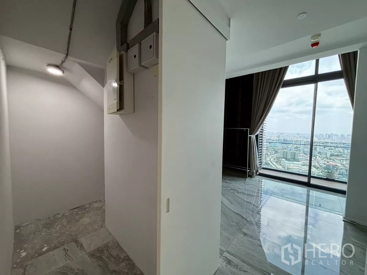 Condominium for sale in Bang Kho Laem, Bangkok - Hallway with a storage niche beside a full-height window overlooking the city.