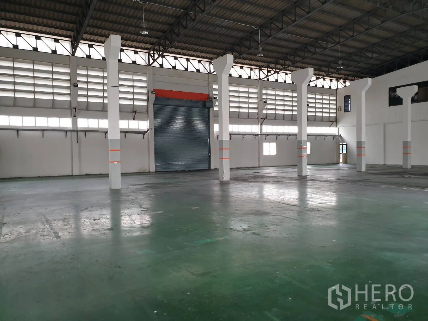 工厂 出租在Bang Pakong, Chachoengsao - 开阔的生产地面，混凝土地坪、白色立柱、百叶窗与大型卷闸门。