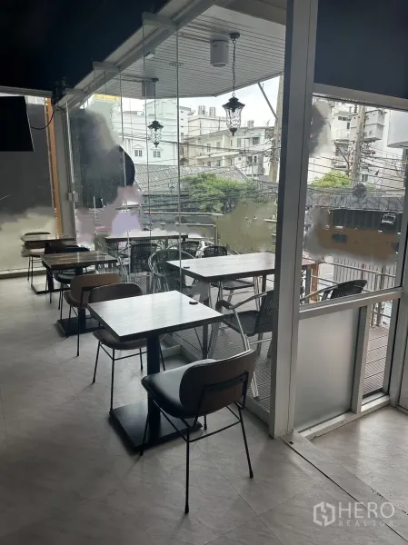 零售空间 出租在Khlong Toei, Bangkok - 窗边双人桌，滑动玻璃门通向阳台座位区。