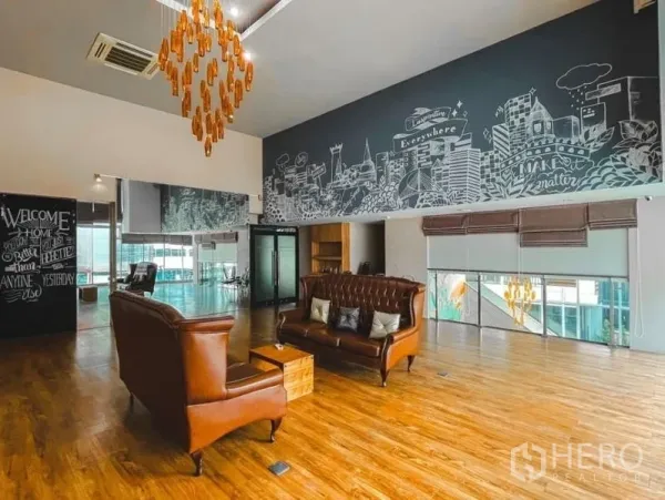Office Space for rent in Lak Si, Bangkok - Creative office lounge featuring leather sofas, large city mural, wood flooring, ceiling chandelier, mirrors and shaded windows.