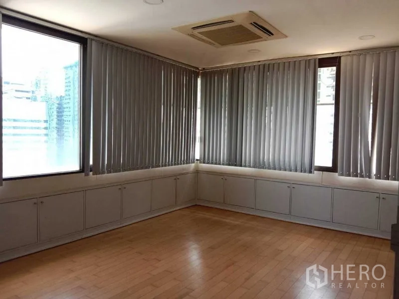 Office Space for rent in Watthana, Bangkok - Corner room with large windows, vertical blinds and light wood flooring.