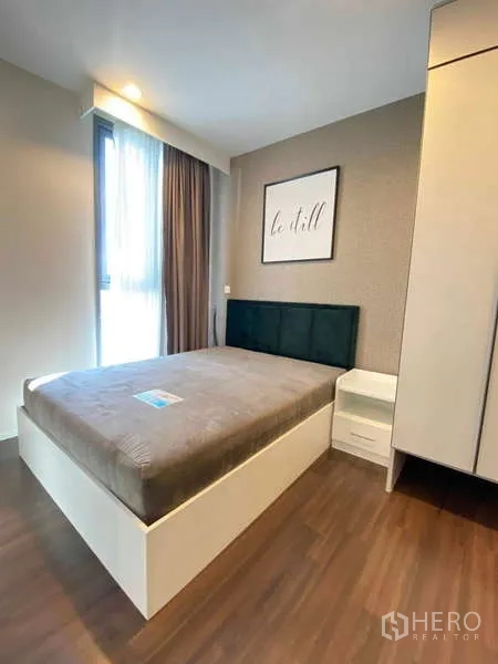 Condominium for rent - Second bedroom with corner window, bed frame, wardrobe and soft lighting.