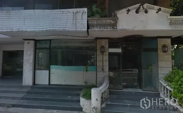 零售空间 出租在Watthana, Bangkok - 曼谷瓦塔那区街边零售店面外立面，宽幅玻璃门窗、入口台阶与经典立柱。