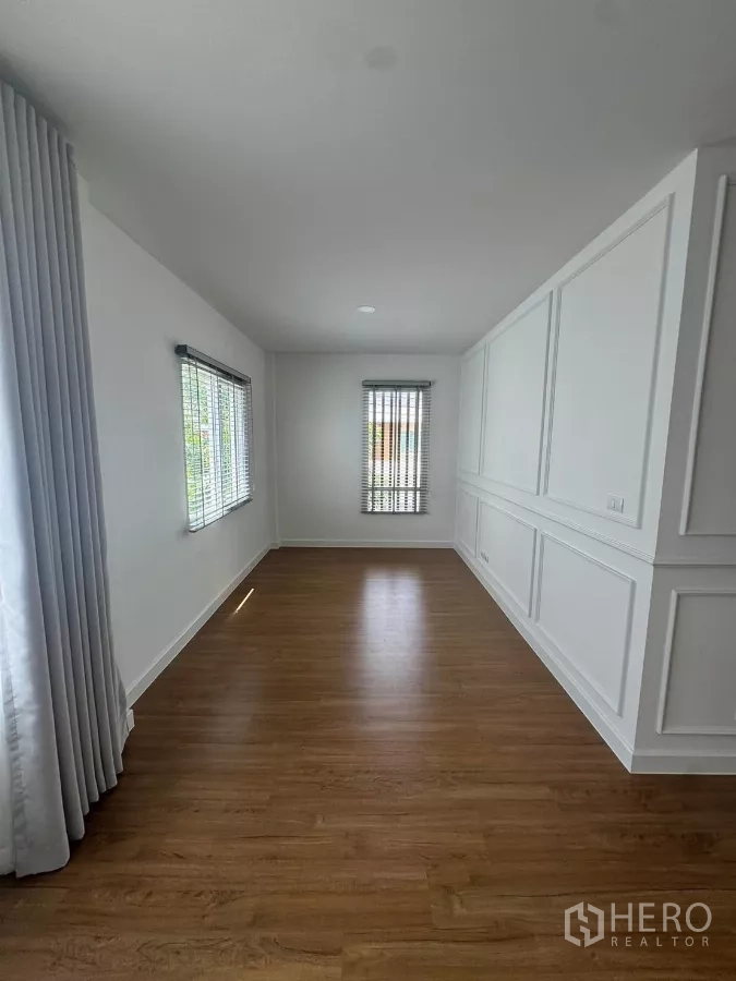 Detached House for rent or sale in Bang Bo, Samut Prakan - Sunlit multipurpose room with two windows, curtains, and wood floors.
