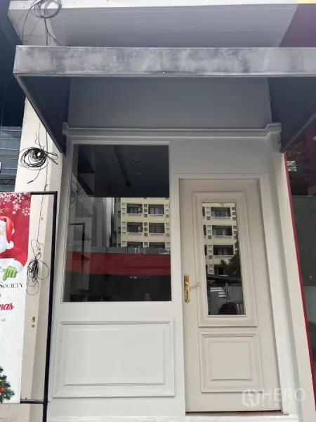 零售空间 出租在Watthana, Bangkok - 白色店面立面，带大展示窗、造型门与雨篷，位于Thonglor商圈。