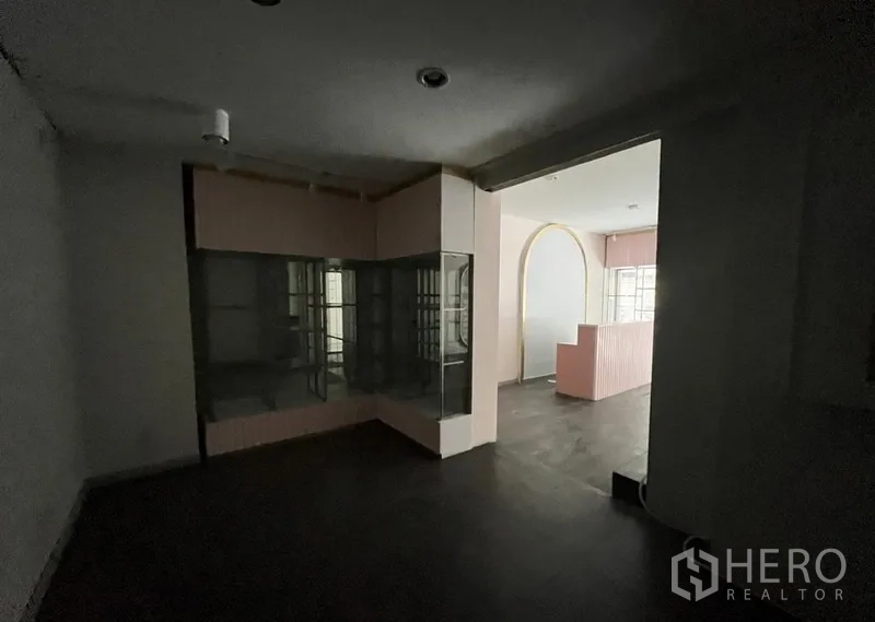 店屋 出租在Watthana, Bangkok - 后侧房间带玻璃展示柜，拱形开口通往前方店面。