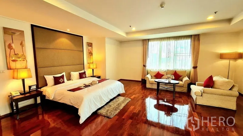 อพาร์ทเมนท์ ให้เช่าในKhlong Toei, Bangkok - ห้องนอนมาสเตอร์กว้างพร้อมเตียงคิง โซฟานั่งเล่น และพื้นไม้เงางาม