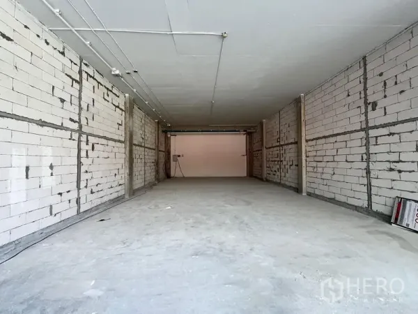 พื้นที่ขายปลีก ให้เช่า - ยูนิตค้าปลีกสภาพเปล่า พื้นคอนกรีต ผนังก่อบล็อกสีขาว และระบบเดินท่อบนฝ้า รูปทรงสี่เหลี่ยมผืนผ้ายาว