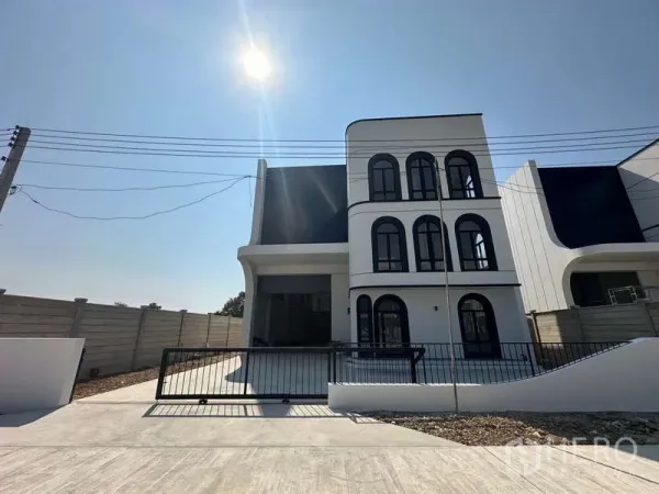 工厂 出售在Lam Luk Ka, Pathum Thani - 现代三层工厂外立面，拱形窗办公楼、带大门的车道与围墙，晴空阳光下。