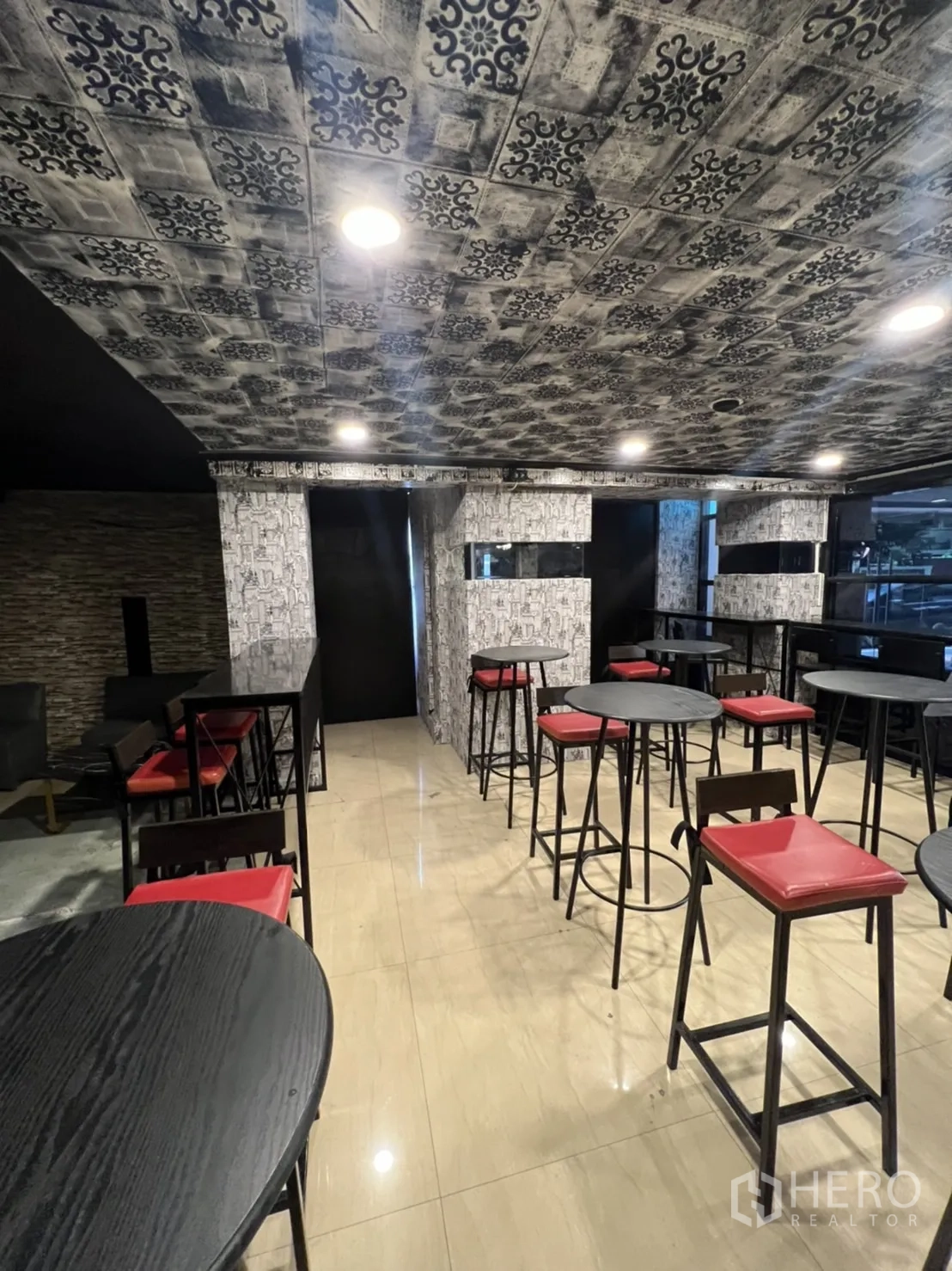 零售空间 出租在Watthana, Bangkok - 高脚餐桌和红色坐垫吧凳，亮面地砖与装饰天花。