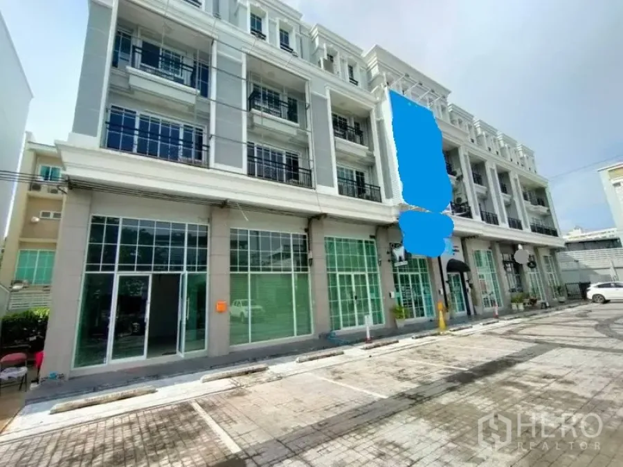 带办公室的家 出租或出售在Bang Na, Bangkok - 四层现代住宅办公楼立面，整片玻璃门面与场内停车位，位于邦那。