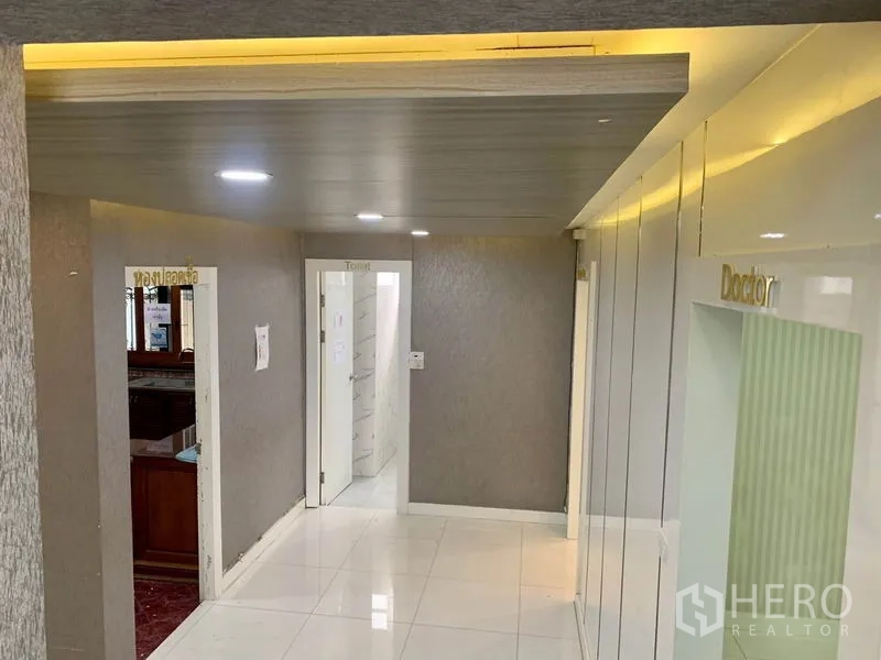 พื้นที่ขายปลีก ให้เช่าในKhlong Toei, Bangkok - โถงทางเดินเพดานฝังไฟ ผนังโทนเทา และประตูหลายห้องรวมถึงห้องน้ำ