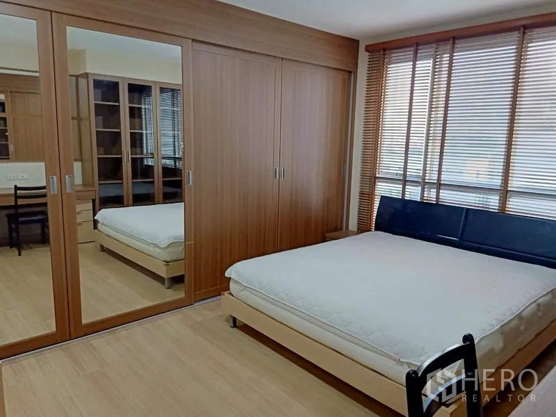 Condominium for rent in Bang Rak, Bangkok - Master bedroom with large bed, mirrored wardrobes and wide windows with blinds.