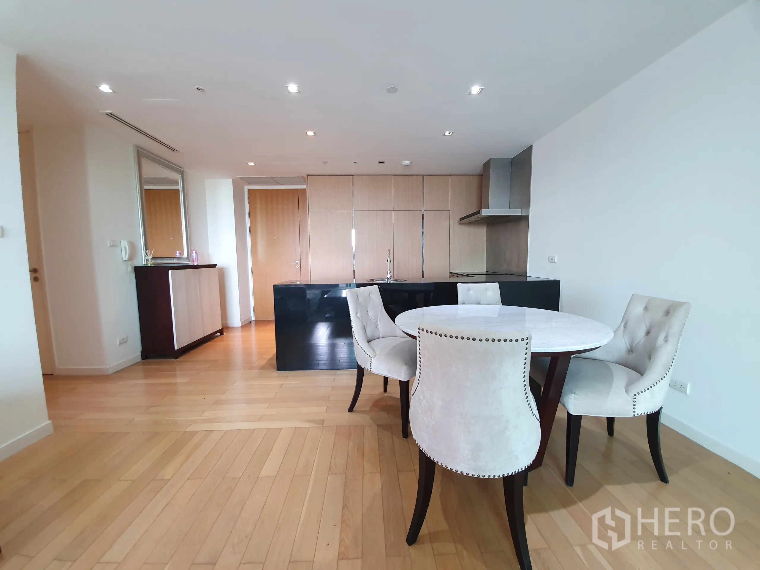 Condominium for rent or sale in Yan Nawa, Bangkok - Dining area with round table and four chairs next to the open kitchen island.