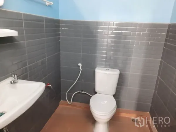 货栈 出租在Khlong Luang, Pathum Thani - 仓库内整洁卫生间，灰色瓷砖，坐便器、手持喷枪与洗手盆齐全。