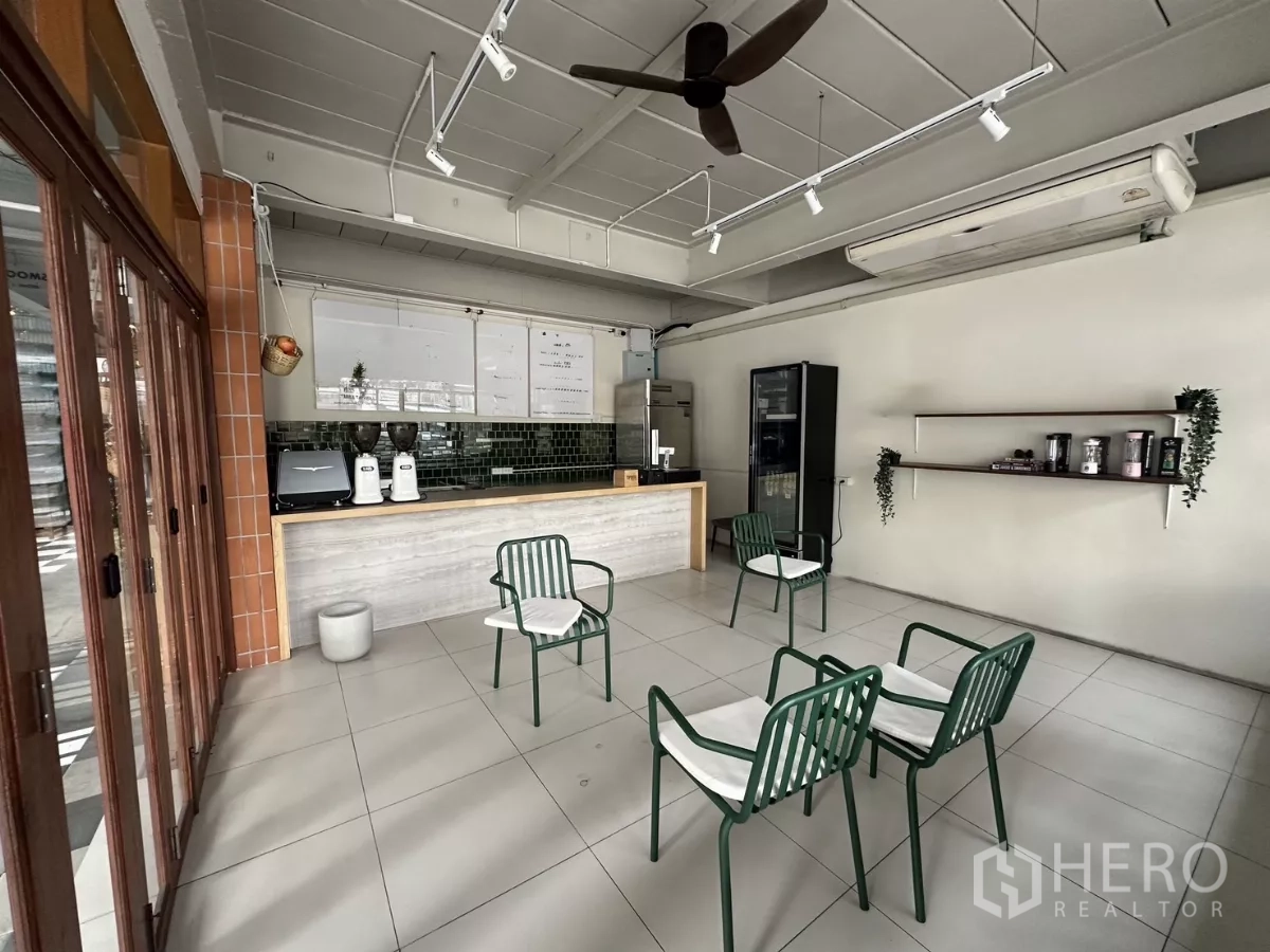 零售空间 出租在Watthana, Bangkok - 前台与咖啡吧区域，绿色瓷砖背景墙，咖啡设备与玻璃店面门。