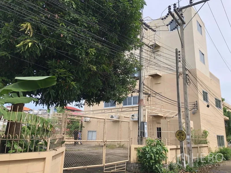 工厂 出租或出售在Bang Lamung, Chon Buri - 工业园侧面视角，带大门、绿化和电线杆。