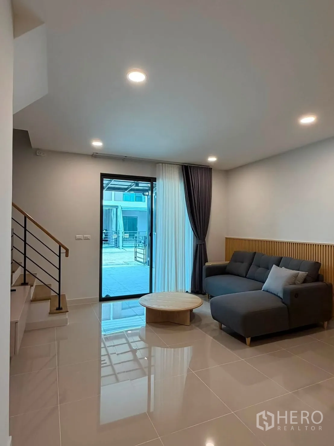 Townhouse for rent in Bang Phli, Samut Prakan - Open-plan living room with L-shaped sofa, coffee table, stairs and sliding door.