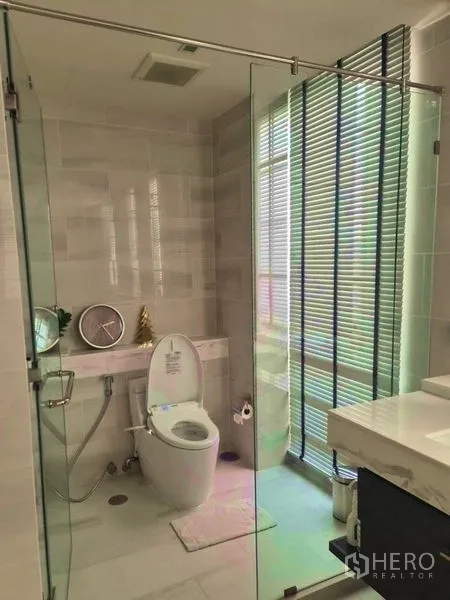 ทาวน์เฮาส์ ให้เช่าในWatthana, Bangkok - ห้องน้ำสว่างพร้อมตู้กระจกกั้นอาบน้ำ โถสุขภัณฑ์ และอ่างล้างหน้า ข้างหน้าต่างมู่ลี่