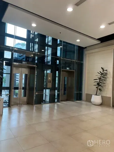 零售空间 出租 - 大堂设玻璃电梯与瓷砖地面，临近商铺区域