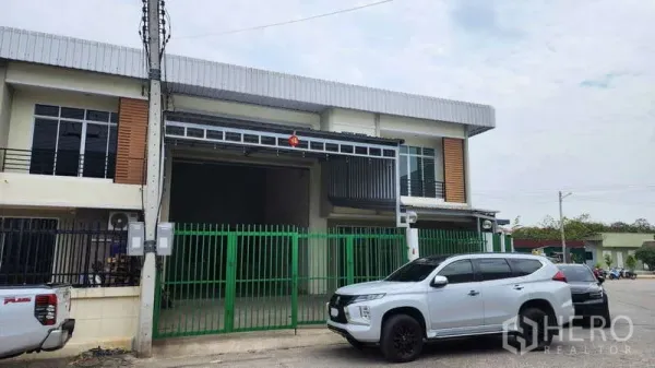 Factory for rent in Samut Sakhon - Modern two-storey factory exterior with green gate, parking and wide driveway.