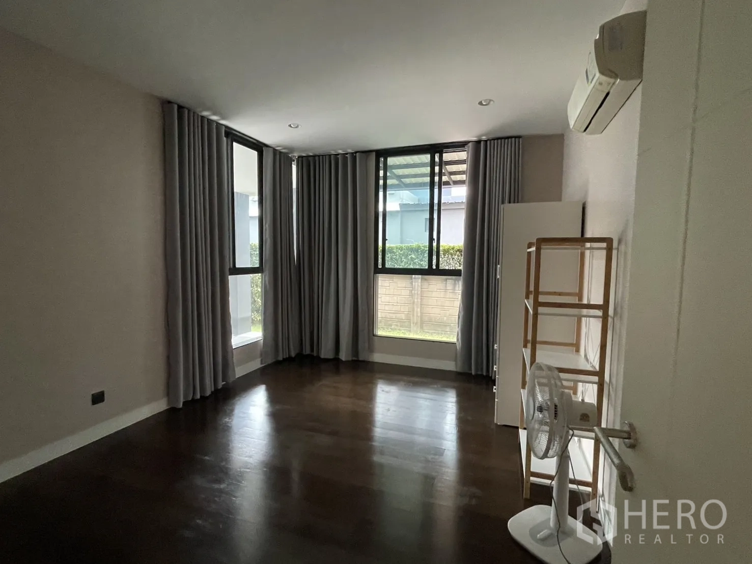 Detached House for rent in Bang Kapi, Bangkok - Spacious room with dark wood floor and multiple windows.