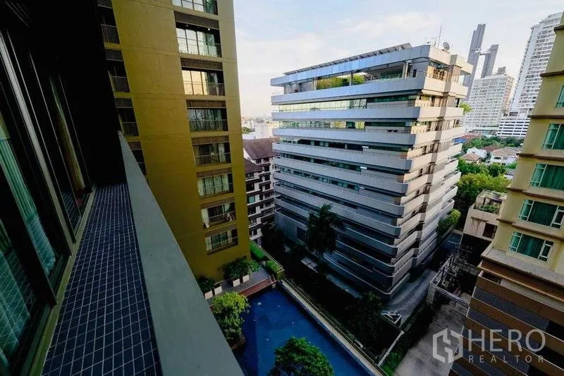 Condominium for rent in Watthana, Bangkok - High‑floor balcony view over pool and neighboring modern buildings.