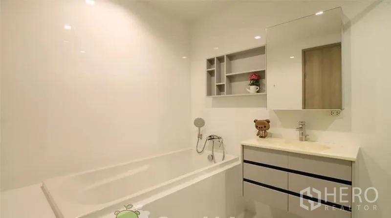 Condominium for rent or sale in Watthana, Bangkok - Clean white bathroom featuring a bathtub, handheld shower and vanity storage.