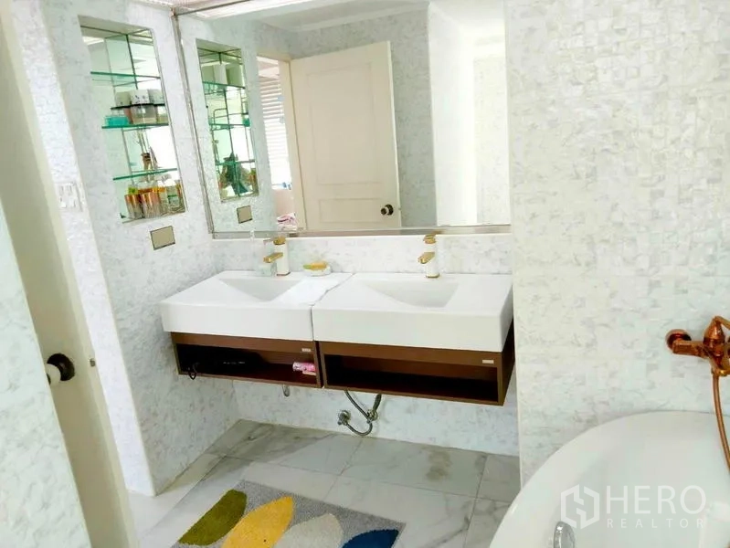 Condominium for rent in Khlong Toei, Bangkok - Bathroom featuring double sinks, wall shelving and a freestanding tub faucet.