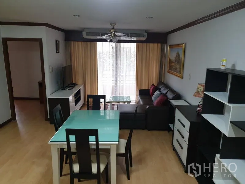 คอนโด ให้เช่าในWatthana, Bangkok - พื้นที่นั่งเล่นและรับประทานอาหารแบบโอเพนพร้อมโต๊ะกระจก ชั้นวางทีวี โซฟา และประตูกระจกสู่ระเบียงพร้อมผ้าม่าน