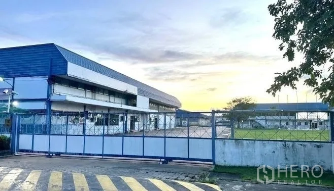 工厂 出租在Bang Bua Thong, Nonthaburi - 傍晚从入口大门望向厂区与绿地的景象。